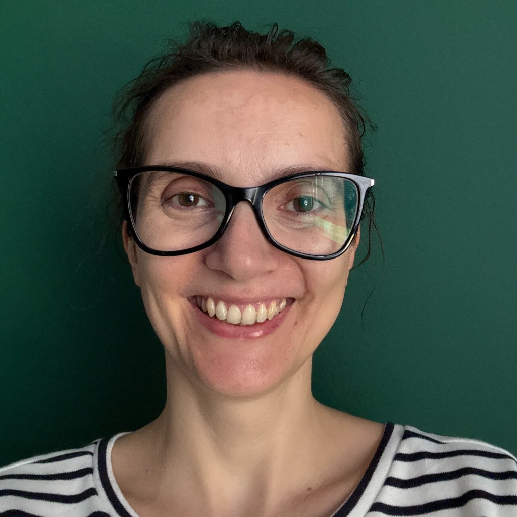 Autorka Ucz się skuteczniej: kursu dla nastolatków - Beata Palińska, uśmiechnięta kobieta z ciemnymi włosami w okularach i koszulce w czarno-białe paski. 